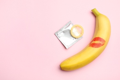 Condom, banana with lipstick kiss mark and space for text on pink background, flat lay. Safe sex