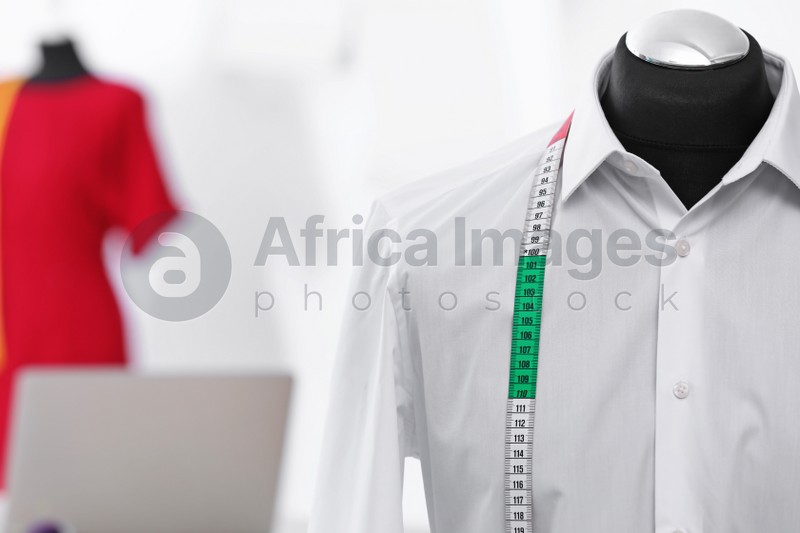 Photo of Mannequin with shirt and measuring tape in tailor studio, closeup