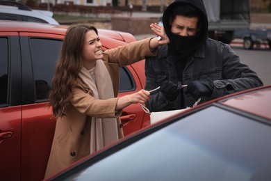 Photo of Woman fighting with thief while he trying to steal her bag on parking lot. Self defense concept