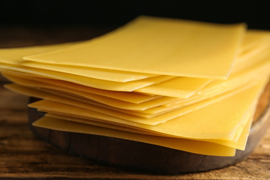 Uncooked lasagna sheets on wooden table, closeup