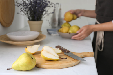 Fresh cut and whole pear on white countertop in kitchen
