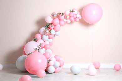 Beautiful composition with balloons and green leaves near beige wall