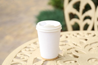 Paper cup of coffee on table outdoors. Takeaway drink
