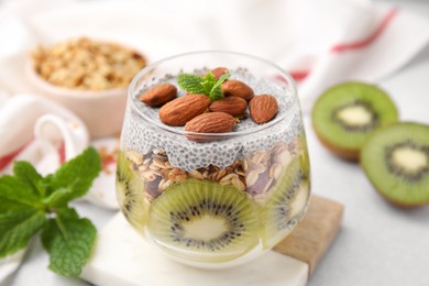 Photo of Delicious dessert with kiwi, chia seeds and almonds on light table, closeup