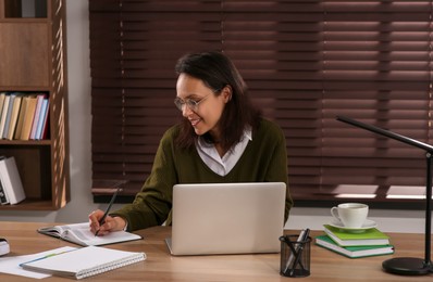 Photo of Woman with modern laptop learning at table indoors