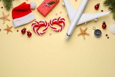 Flat lay composition with toy airplane, Santa hat and space for text on yellow background. Christmas vacation