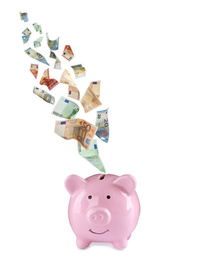 Euro banknotes falling into pink piggy bank on white background