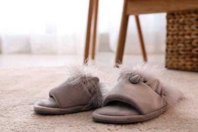 Pair of light grey slippers on floor in room