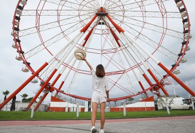 Young woman near Ferris wheel outdoors, low angle view